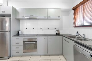 Une cuisine moderne dotée d’appareils électroménagers en acier inoxydable, de meubles blancs et d’un four encastré.