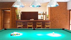 A pool table with balls, a bar area with chairs, and pendant lighting. - Bayu Gita Beachfront Villa (Kec. Sukawati, Kabupaten Gianyar)