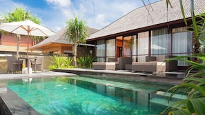 A poolside area with a clear pool, lounge chairs, and a covered seating area. - Bayu Gita Beachfront Villa (Kec. Sukawati, Kabupaten Gianyar)