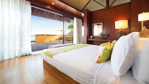 A hotel room with a large bed, a view of the ocean, a wooden deck, and a balcony with a view of palm trees. - Bayu Gita Beachfront Villa (Kec. Sukawati, Kabupaten Gianyar)