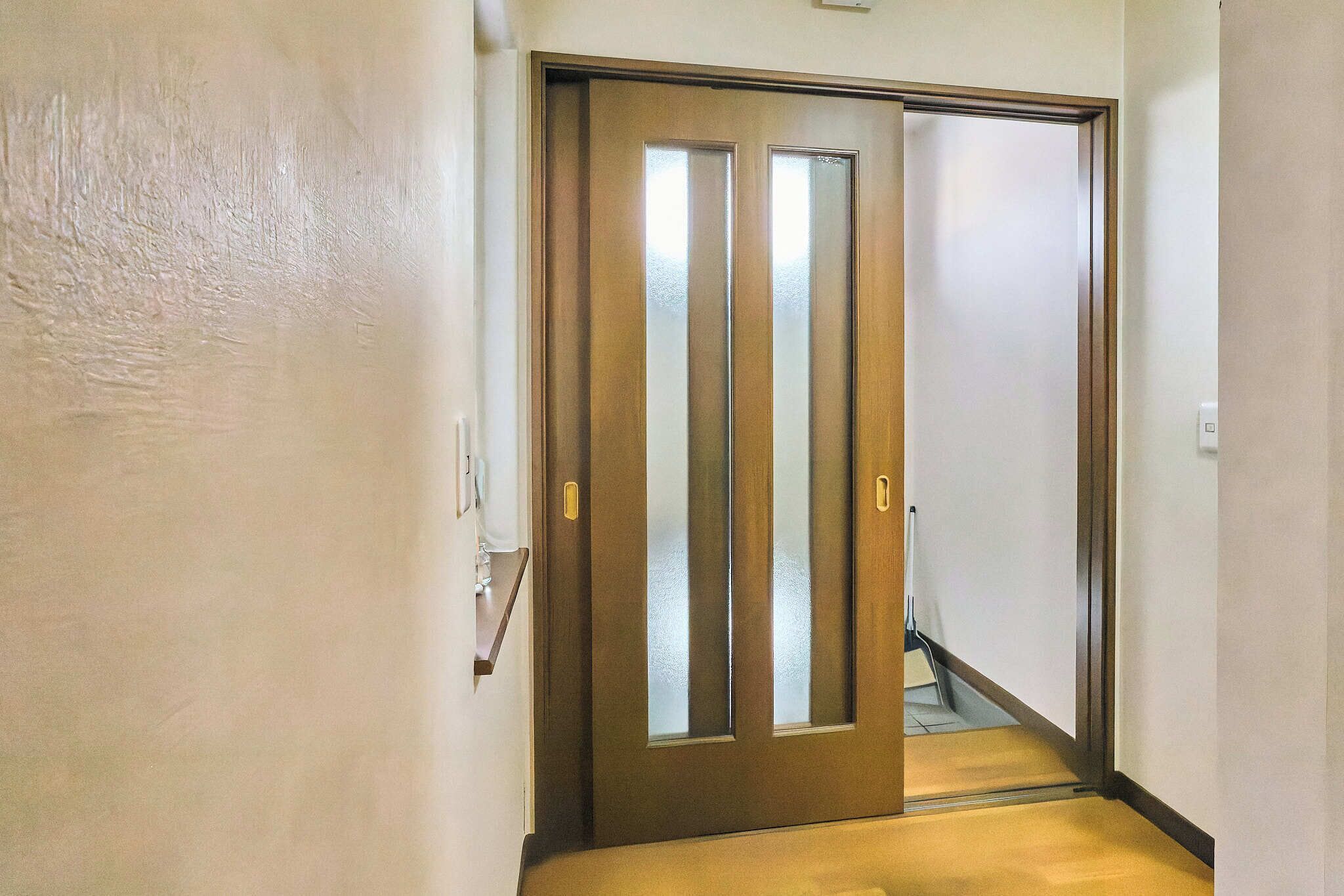 A hallway with a wooden door with vertical frosted glass panels.