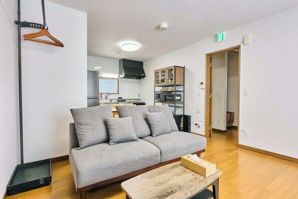 Una sala de estar moderna con un sofá, una mesa de centro y una cocina al fondo.