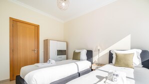 Et hotelværelse med to senge, et garderobeskab, et natbord med en lampe og et håndklæde på sengen.