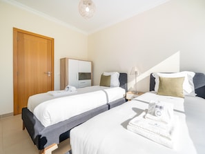 Ein Hotelzimmer mit zwei Betten, einem Kleiderschrank, einem Nachttisch mit Lampe und einem Handtuch auf dem Bett.