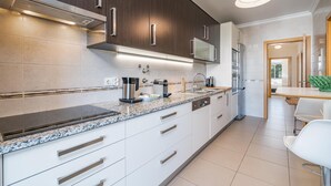 Et moderne køkken med mørke træskabe, rustfrie hvidevarer og en bordplade i granit.