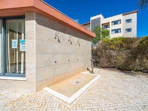 Ein Gebäude mit Kachelfassade, Glastür und einer kleinen Außendusche.