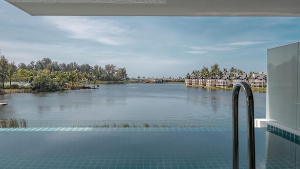 An infinity pool with a view of a lake and resort buildings. - The Angsana Oceanview Residences Unit 235 (Choeng Thale)