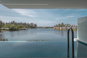 An infinity pool with a view of a lake and resort buildings.