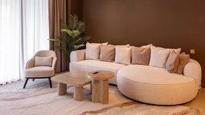 A living room with a sofa, armchair, and two wooden side tables. - The Angsana Oceanview Residences Unit 235 (Choeng Thale)