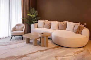 Una sala de estar con un sofá, un sillón y dos mesitas de madera.