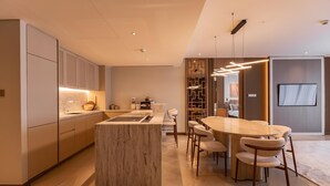 A modern kitchen with a central island, a dining area with a round table and chairs, and a living space with a TV. - The Angsana Oceanview Residences Unit 235 (Choeng Thale)