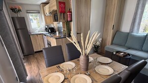 Eine moderne Küche mit Holzausstattung, einem Esstisch für vier Personen und einem Sofa im Wohnbereich.