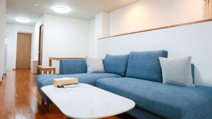 Uma sala de estar moderna com um sofá azul, uma mesa de centro branca e um banco de madeira.