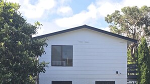 Une maison mobile blanche d’un seul étage, avec un toit foncé, une fenêtre et une cour clôturée.