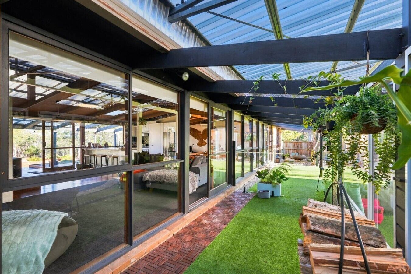 A modern interior with a glass-enclosed patio, a small artificial grass area, and hanging plants.