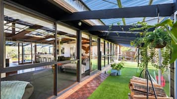 A modern interior with a glass-enclosed patio, a small artificial grass area, and hanging plants.