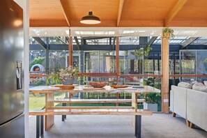 Uma cozinha moderna com um banco de madeira, uma mesa de jantar e um forno embutido.