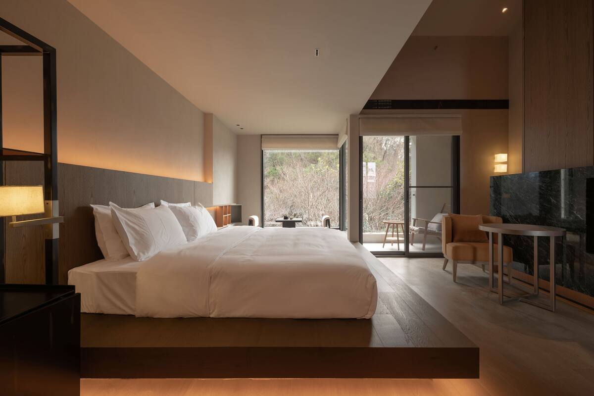 Una habitación de hotel moderna con una cama grande, un escritorio y un televisor.