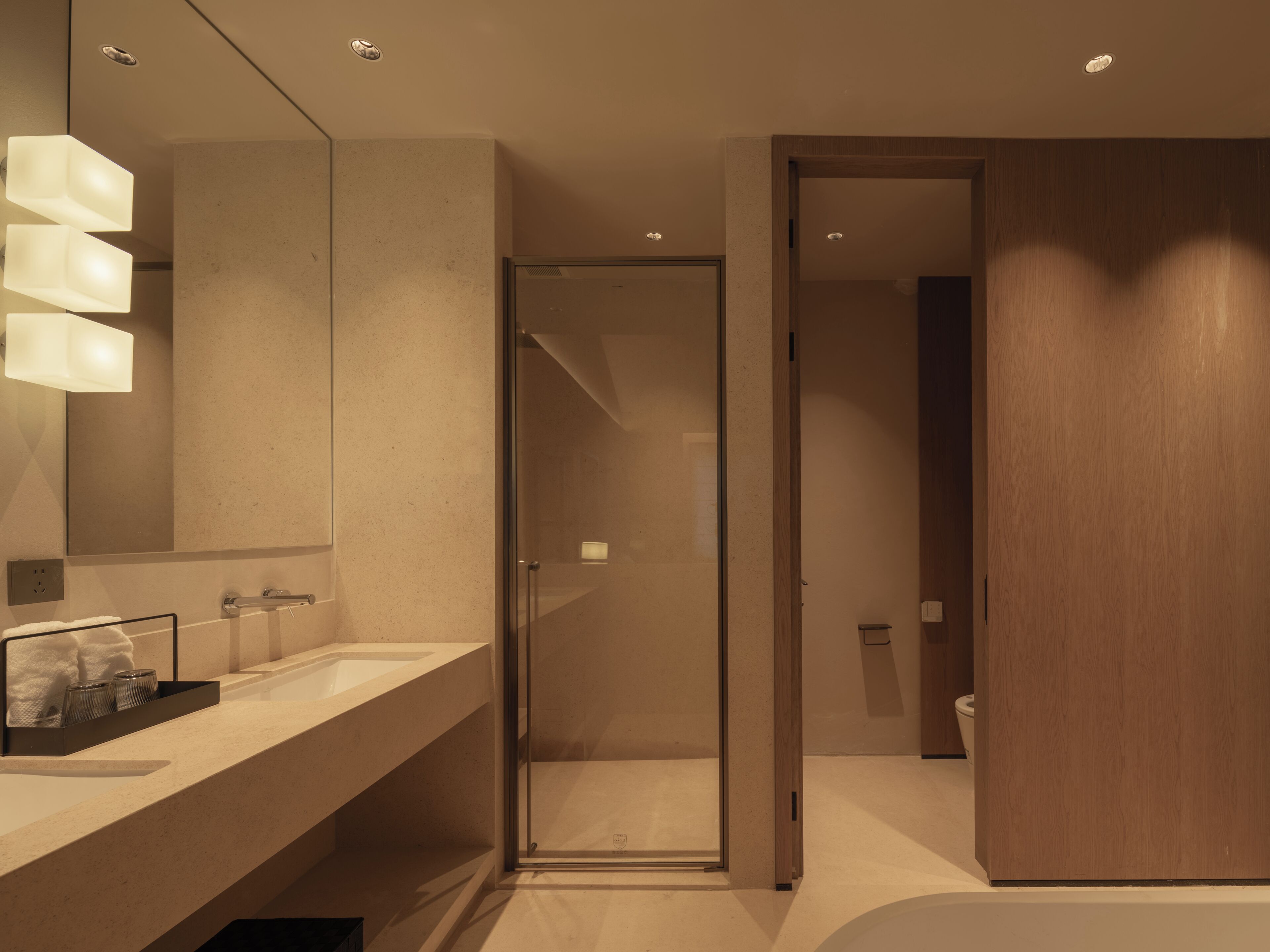A modern bathroom with a large mirror, a glass shower enclosure, and a wooden door.