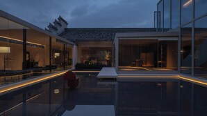 A modern building with large glass windows, a reflective pool, and traditional architectural elements. - Hayama Pagoda Villa (Taizhou)