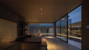 A modern interior with a wooden bench, a long table, and a glass wall offering a view of the outside. - Hayama Pagoda Villa (Taizhou)