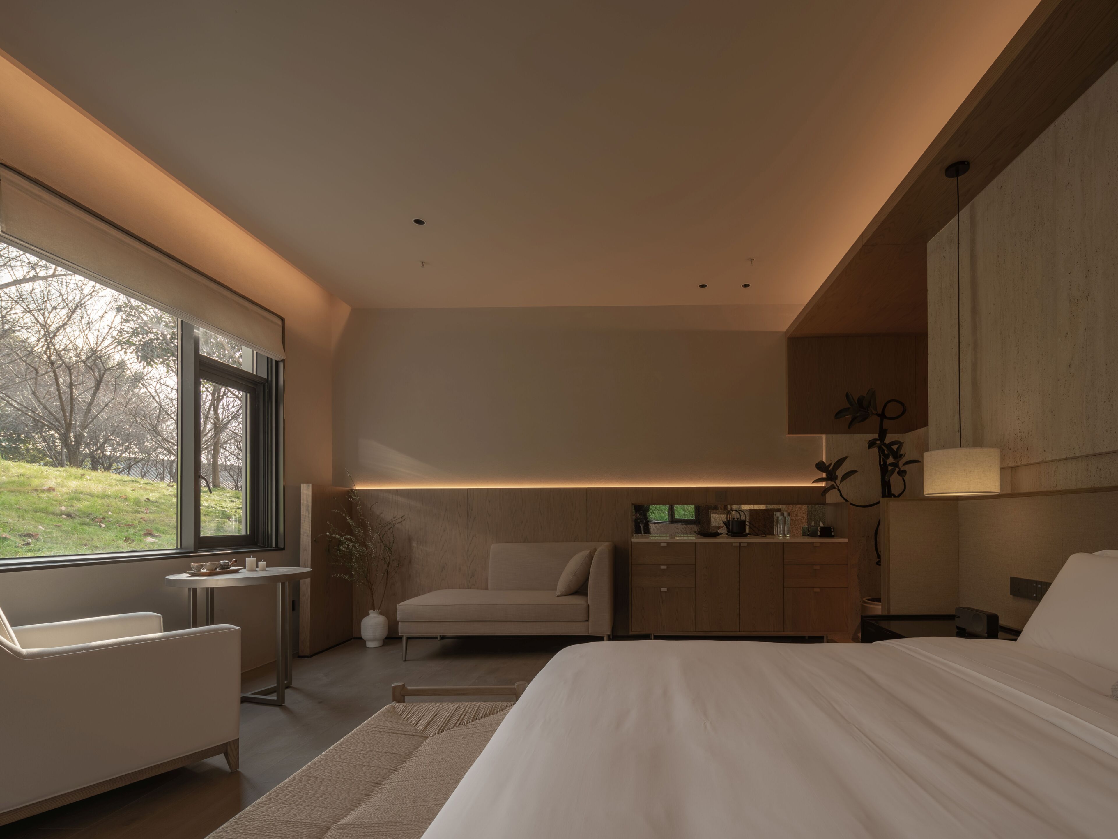 Un dormitorio moderno con una cama grande, un escritorio, una silla y una mesita de noche.