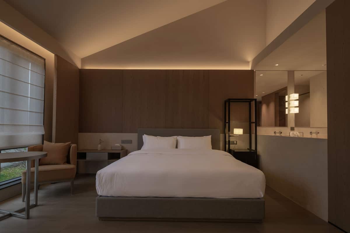 Une chambre moderne avec un grand lit, des tables de chevet, une chaise et un miroir.