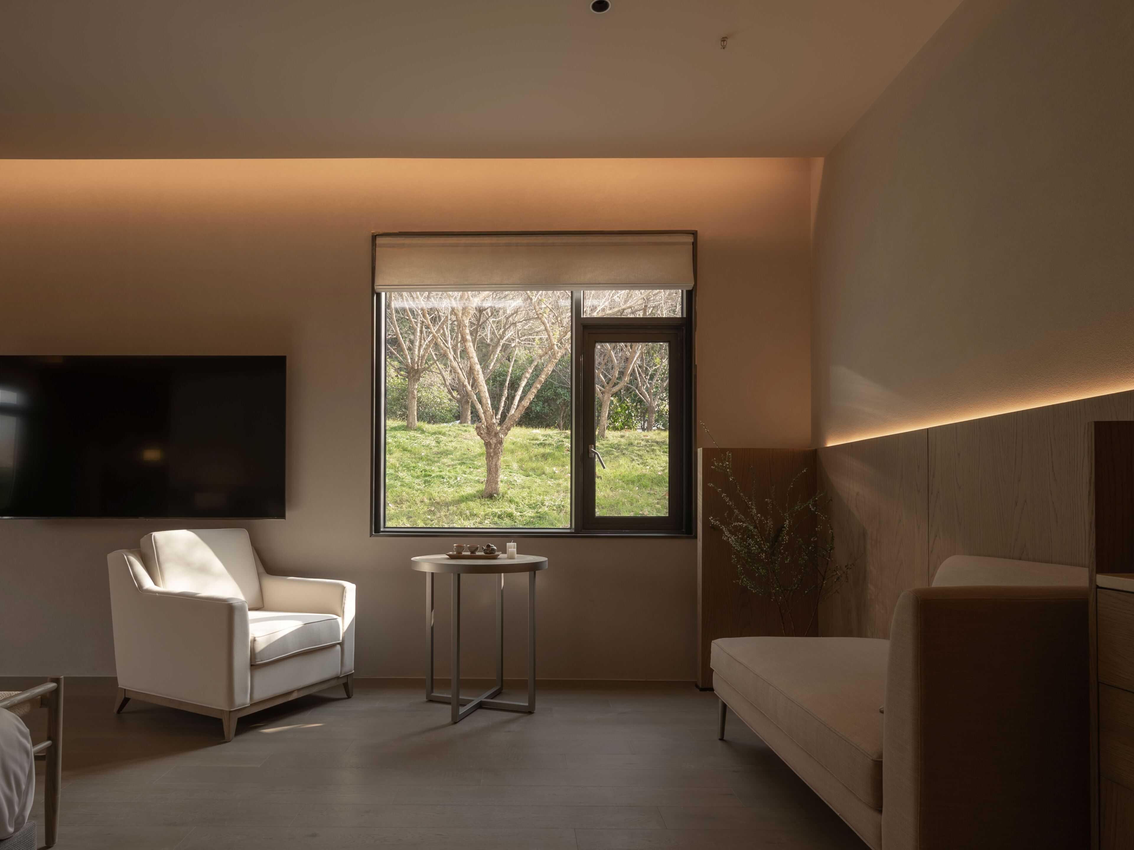 A modern living room with a sofa, a small table, and a TV mounted on the wall.