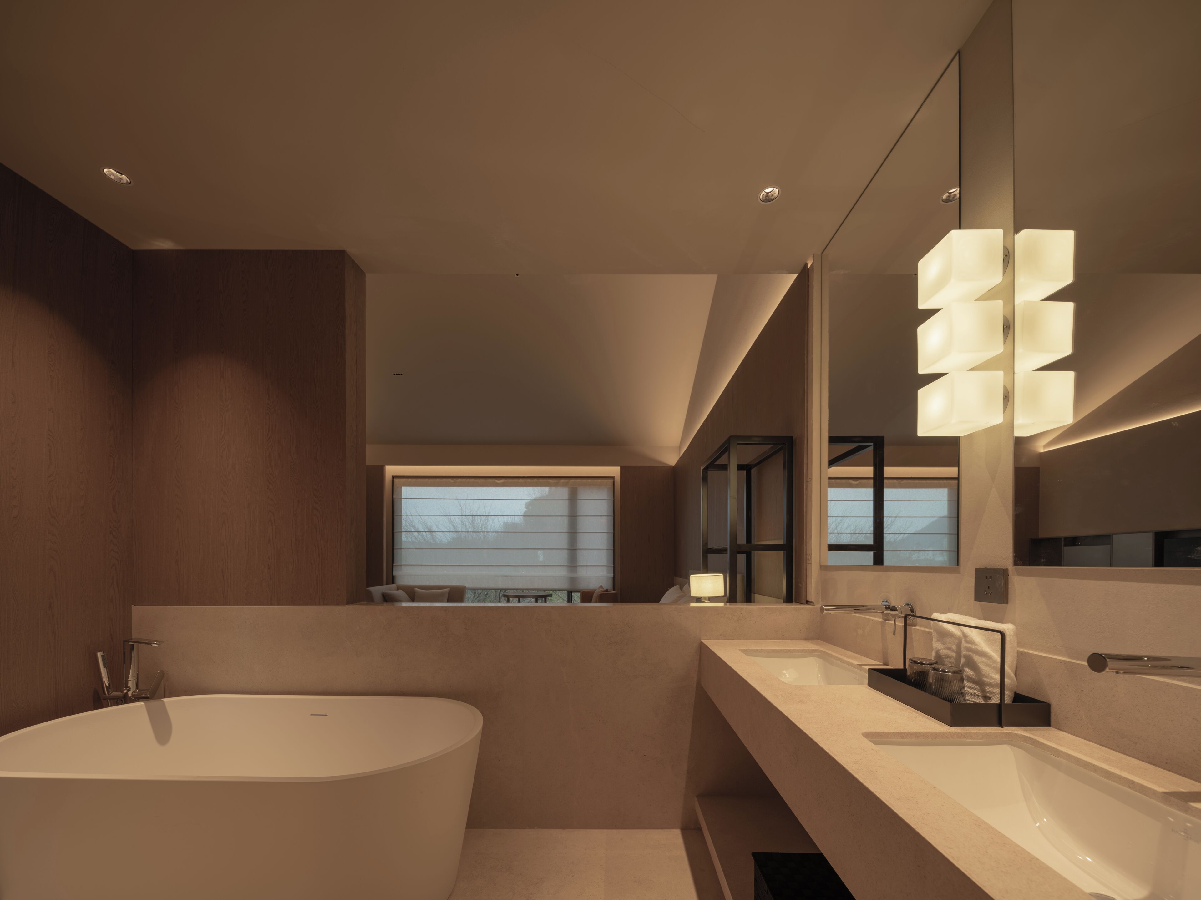 A modern bathroom with a large bathtub, dual sinks, and a large mirror.
