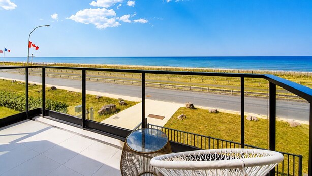 Un balcon avec vue sur la plage, une route et des drapeaux.