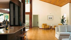 Ein geräumiger Wohnbereich mit Holzboden, eine Küche mit Bar und ein weißes Sofa.