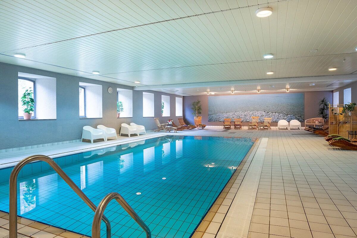Dive into a serene indoor pool with relaxing loungers.