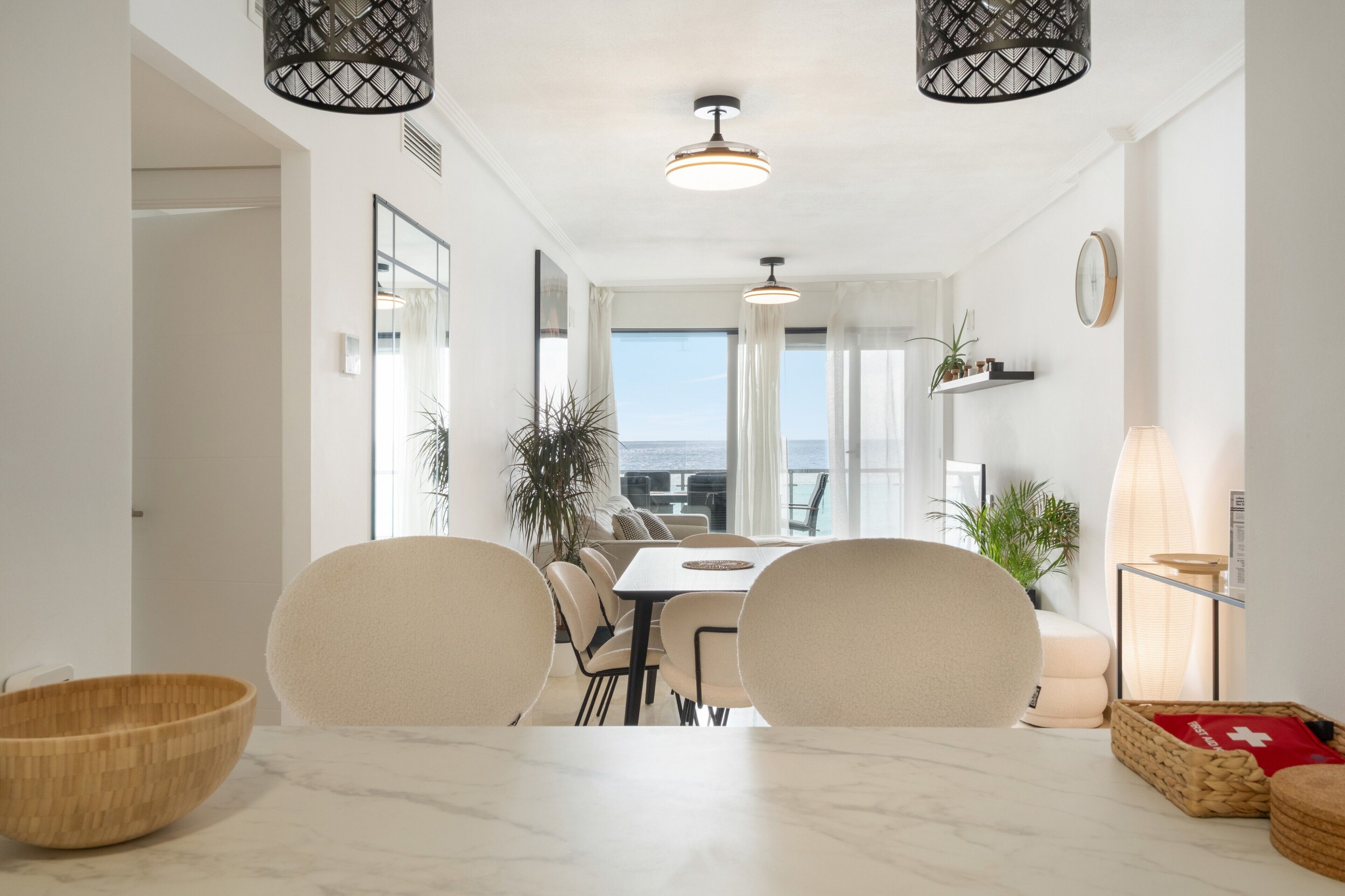 A dining area with a marble table, chairs, and a view of the sea.