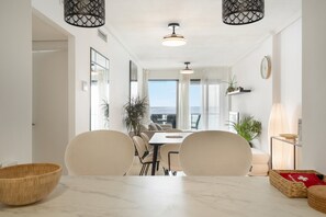 Un comedor con una mesa de mármol, sillas y vista al mar.