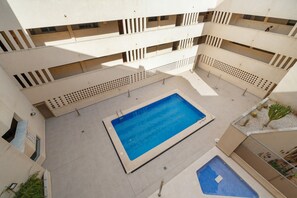 Un edificio de varios niveles con un patio central que tiene una piscina.