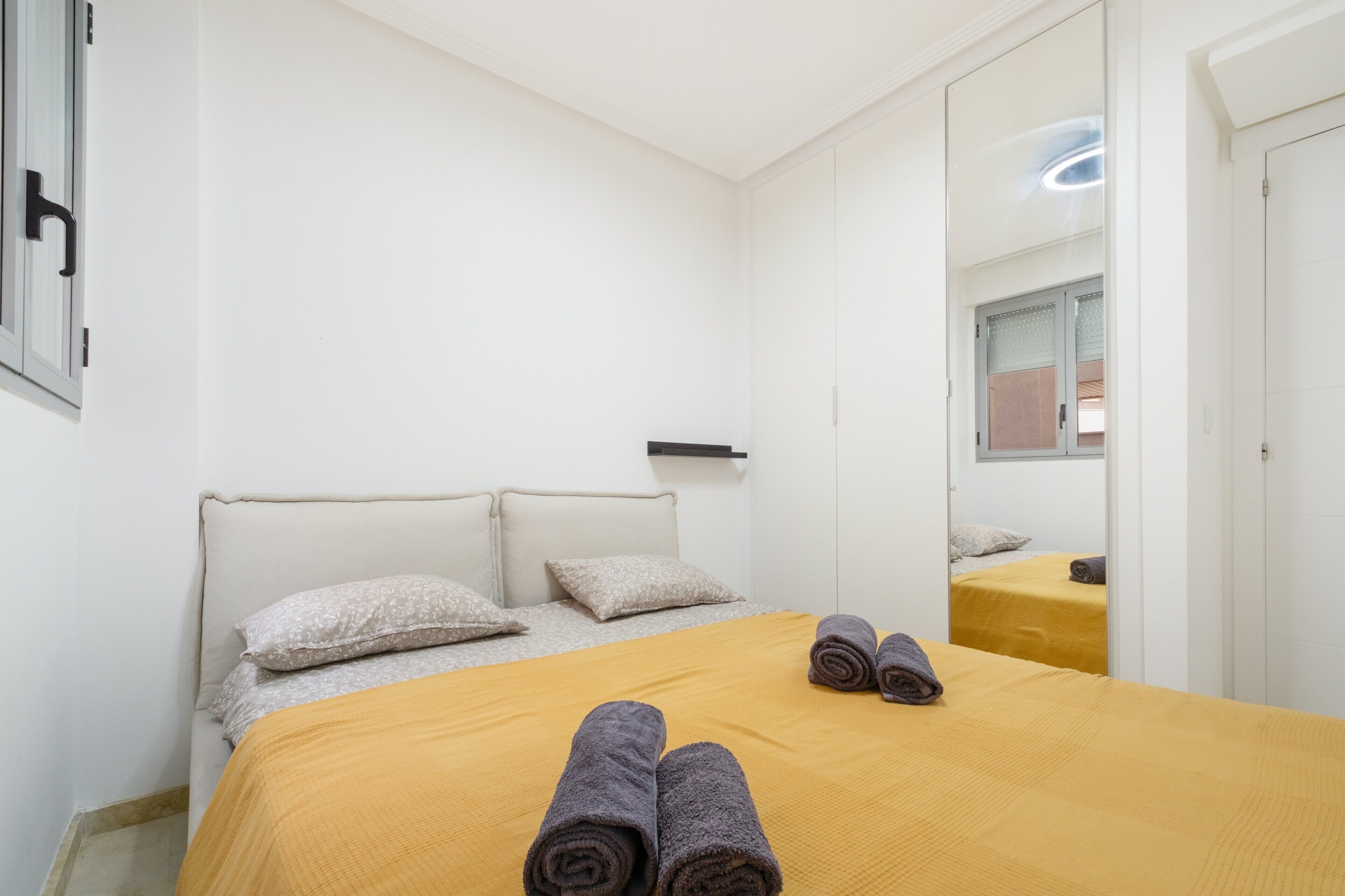 Una habitación de hotel con una cama, un espejo y una ventana.