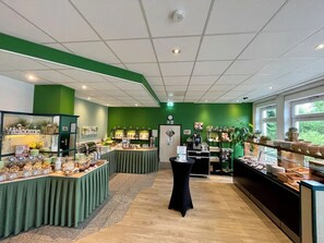 Ein Bereich mit einem Buffet, verschiedenen Speiseausgaben, einer Kaffeebar und einer Rezeption.