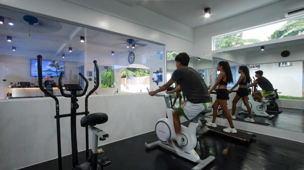 Un gimnasio con equipo cardiovascular, una recepción y un espejo grande que refleja el espacio.