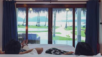 A room with a bed, a view of a beach, and a sign above the window.