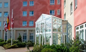 Ein modernes Gebäude mit Wintergarten, zahlreichen Fenstern und Flaggen.