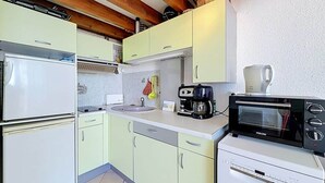 Eine kleine Küche mit Kühlschrank, Kaffeemaschine, Toaster und Spüle.