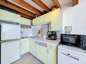 Eine kleine Küche mit Kühlschrank, Kaffeemaschine, Toaster und Spüle.