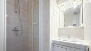 Ein Badezimmer mit Dusche, Waschbecken und Spiegel.