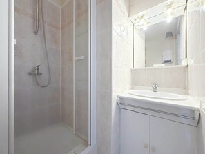 Ein Badezimmer mit Dusche, Waschbecken und Spiegel.