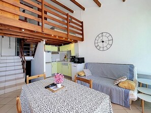 Ein gemütliches Zimmer mit Esstisch, Sofa und einer Treppe, die zu einer oberen Ebene führt.