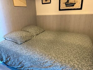 Ein Bett mit floralem Bettzeug, einem Kopfkissen und einem Bilderrahmen mit einem Segelboot an der Wand.
