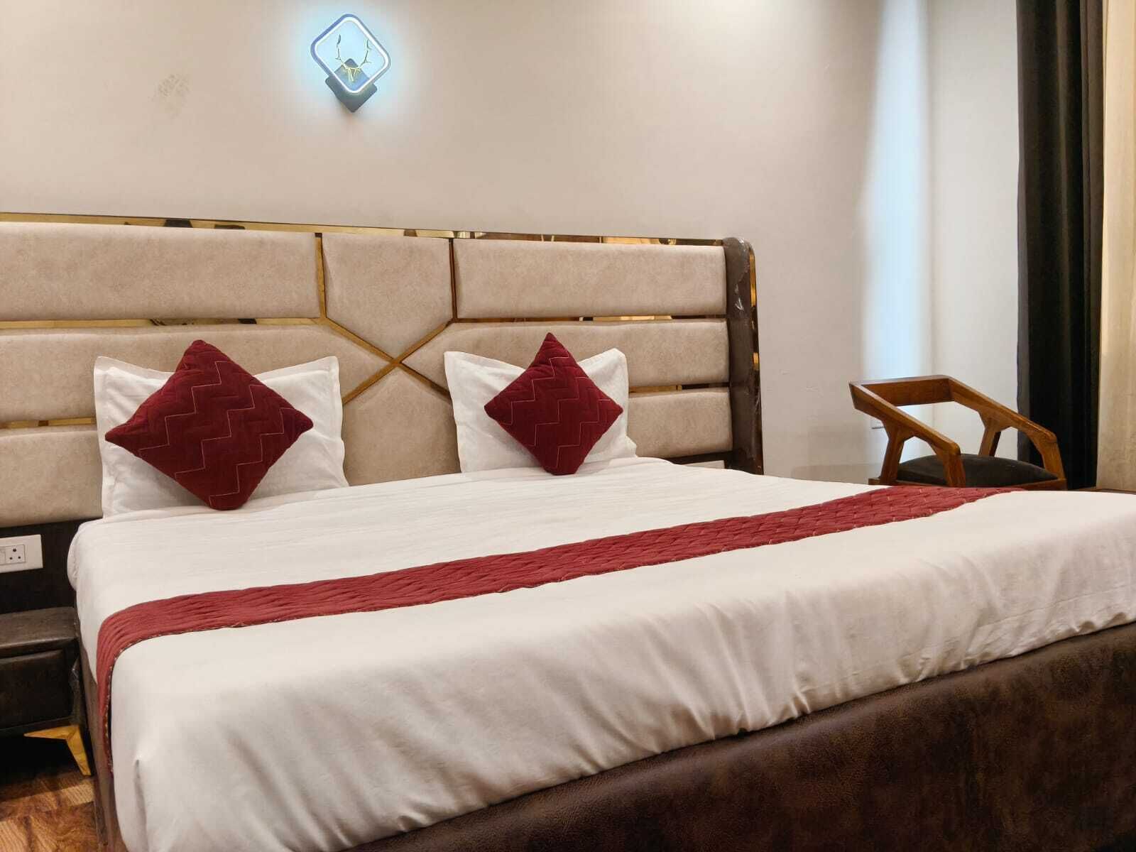 Cama bem arrumada com cabeceira, duas almofadas e manta vermelha.