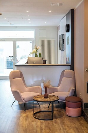 Een moderne woonkamer met twee comfortabele banken, een ronde houten salontafel en een klein pouf.