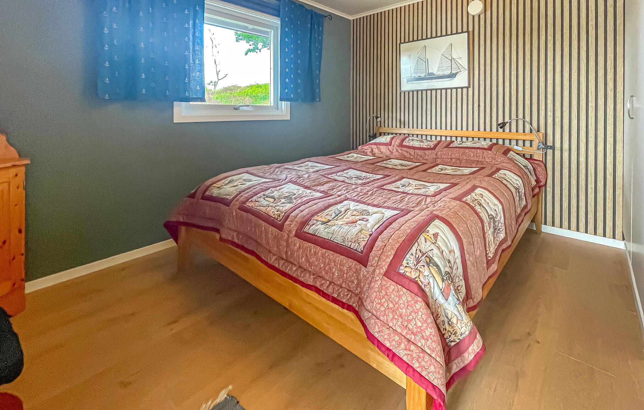 Une chambre à coucher avec un lit, une fenêtre avec des rideaux, un tableau accroché au mur et une porte en bois.