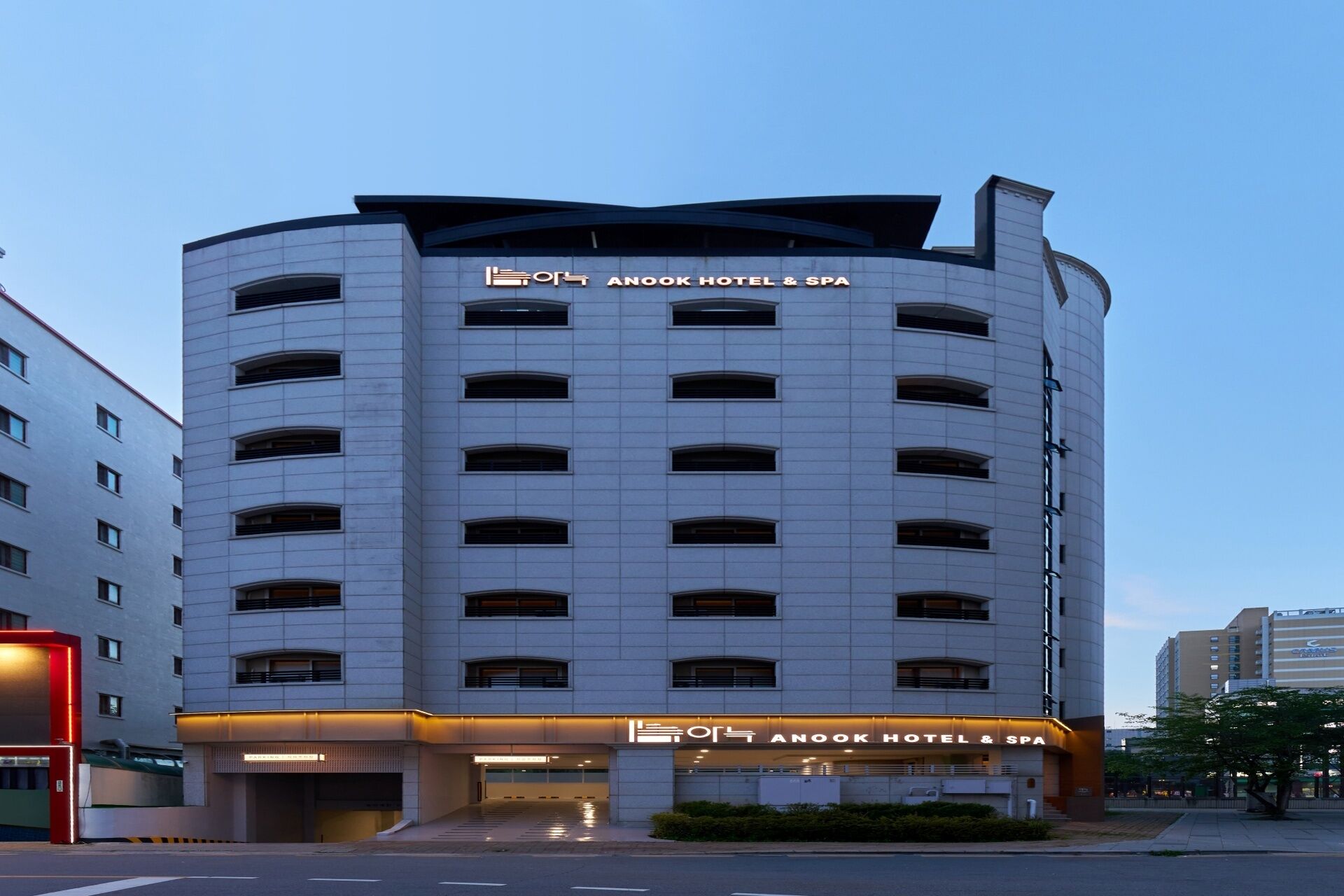 A modern hotel building with a prominent sign for Anook Hotel & Spa.